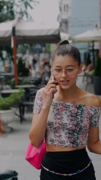 차가운 커피를 들고있는 그녀가 거리를 걸어으로 사랑스러운 소녀는 적극적으로 전화로 — 비디오