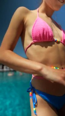 Canlı bikinili genç bir kadın havuz kenarında dans ediyor. Yüksek kalite 4k görüntü