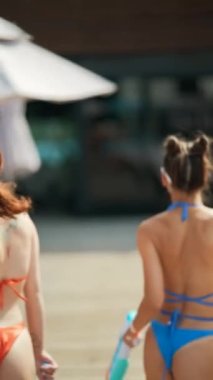 Parlak mayo giymiş, havuz kenarında su tabancası tutan kızların mavi arka planı. Yüksek kalite 4k görüntü