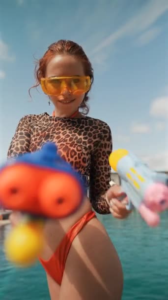 ビキニの明るくスタイリッシュな女の子は プールサイドで水銃を手にポーズします 高品質の4K映像 — ストック動画