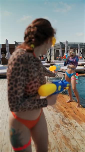 水の銃を手に持って 明るい水着の活気ある女の子は遊び心のある水の戦いに従事しています 高品質の4K映像 — ストック動画