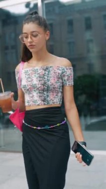 Elinde kahve ve akıllı telefon olan güzel bir genç kız iş çıkış saatinde acele ediyor. Yüksek kalite 4k görüntü