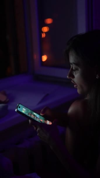 一位年轻妇女深夜在一台计算机监视器前工作 手里拿着一部电话 高质量的4K镜头 — 图库视频影像