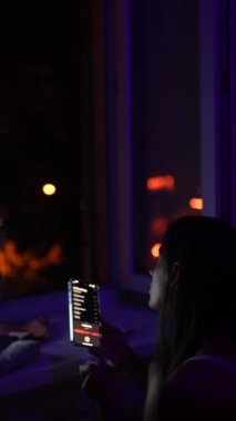 Gece yarısı sahnesi: dizüstü bilgisayarı üzerinde çalışan ve telefonda sohbet eden genç bir kız. Yüksek kalite 4k görüntü