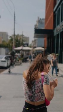 Modaya uygun, genç bayan şehir sokaklarında koşuşturuyor, iş programının gerisinde kalıyor. Yüksek kalite 4k görüntü