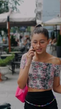 Elinde soğuk bir kahve tutarken, güzel, genç bir kız şehir sokaklarında yürürken telefonda aktif olarak sohbet ediyor. Yüksek kalite 4k görüntü