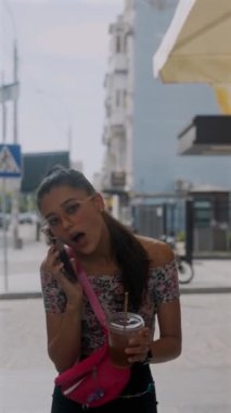 Elinde kahve ve akıllı telefon tutan hayat dolu genç kız işe zamanında yetişmek için acele ediyor. Yüksek kalite 4k görüntü