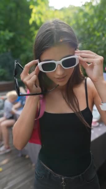 Όμορφο Κορίτσι Που Δοκιμάζει Καλοκαιρινά Γυαλιά Στην Αγορά Υψηλής Ποιότητας — Αρχείο Βίντεο