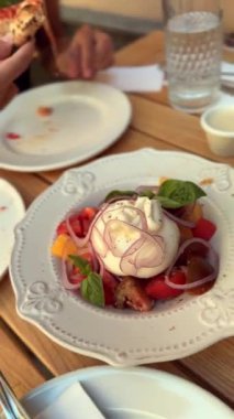 Bir restoranda, kız burrata peyniri tadıyor ve tadını çıkarıyor. Yüksek kalite 4k görüntü