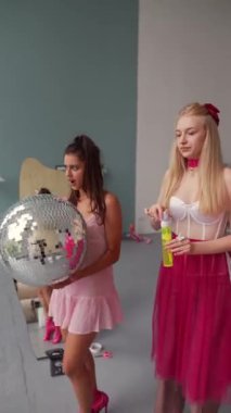 Pembe elbiseli kızlar, bebek gibi giyinmiş, disko topu ve sabun köpüğüyle dans ediyorlar. Yüksek kalite 4k görüntü