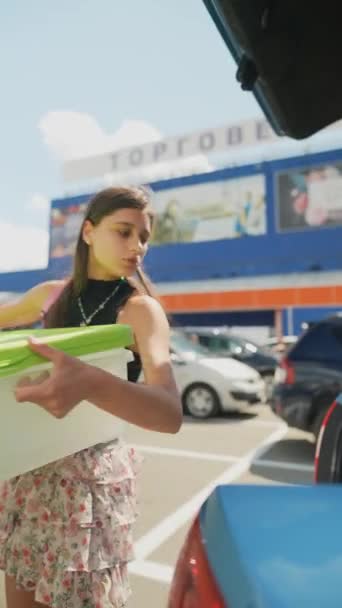 若い女性がスーパーマーケットの近くの車のトランクに買い物袋を置いている 高品質の4K映像 — ストック動画