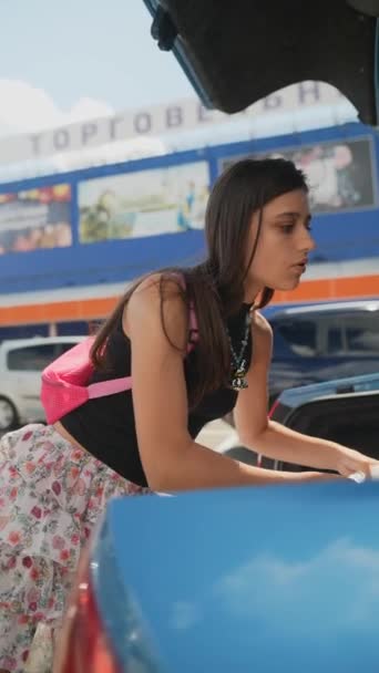 女の子はスーパーマーケットの隣のトランクにショッピングバッグを入れています 高品質の4K映像 — ストック動画