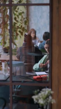Kulaklık takan genç bir kadın, bir kahve dükkanında dizüstü bilgisayarla sohbet ediyor. Yüksek kalite 4k görüntü