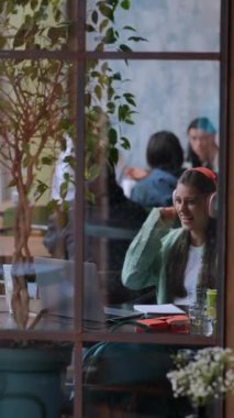 Bir kafede, bir kız dizüstü bilgisayarı üzerinde çalışırken kulaklık kullanıyor. Yüksek kalite 4k görüntü