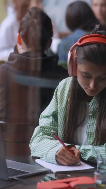 Kawiarni Uczennica Używa Laptopa Nosi Słuchawki Pisze Notatniku Wysokiej Jakości — Wideo stockowe