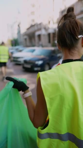 ボランティアの少女が街の通りでゴミを集め それを専門のゴミ袋に入れています 高品質の4K映像 — ストック動画