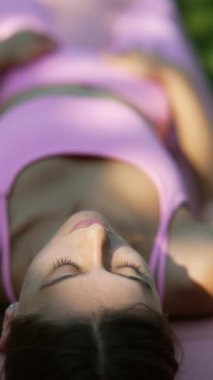 Parktaki çimlerin üzerinde genç bir kadın yatıyor ve üzerinde bir sinek uçuyor. Yüksek kalite 4k görüntü