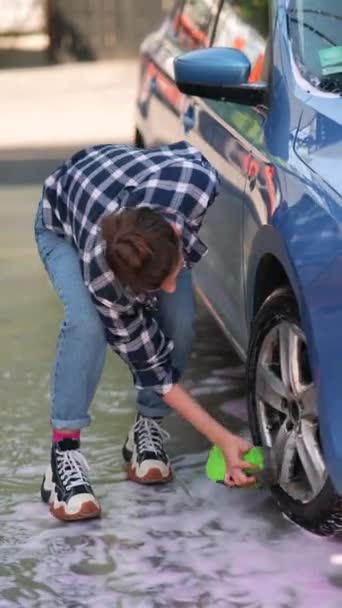 洗車場では 見事な若い女性が車の車輪を掃除しています 高品質の4K映像 — ストック動画