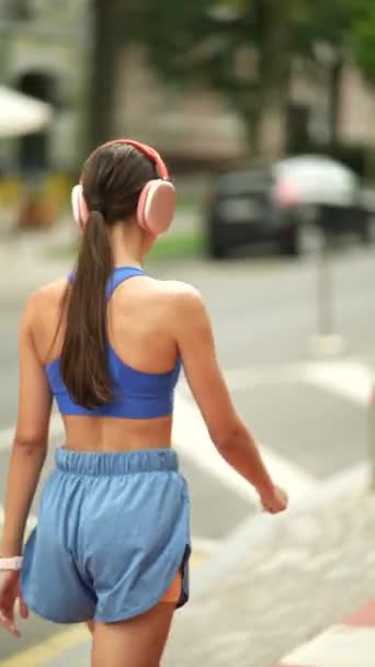 一个穿着运动服和耳机的漂亮姑娘正在城里做她的晨跑 高质量的4K镜头 — 图库视频影像