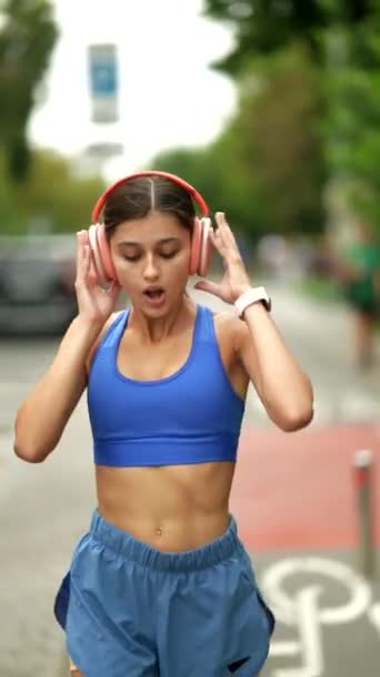 一个穿着运动服的漂亮姑娘带着耳机去城里参加她的晨跑 高质量的4K镜头 — 图库视频影像