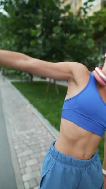 Sportieve Koptelefoon Een Mooi Meisje Atletische Kleding Warmt Haar Armen — Stockvideo