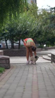 Çevrelerindeki şehir manzarasıyla, güzel genç bir kadın köpeğiyle birlikte sokaklarda yürüyor. Yüksek kalite 4k görüntü