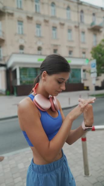 그녀의 달리기에 운동복과 헤드폰에 사랑스러운 소녀는 그녀의 따뜻한 루틴의 일환으로 — 비디오