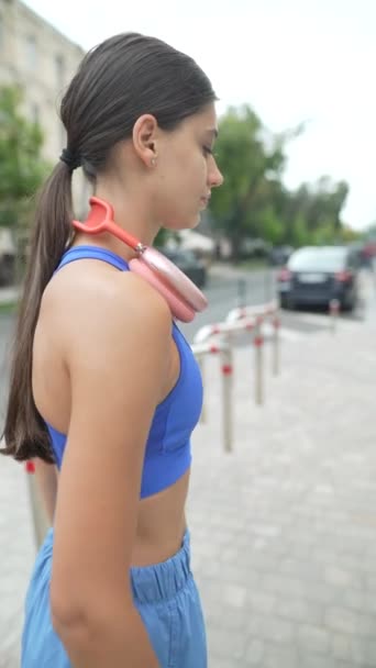 一名身穿运动服 戴着耳机的年轻漂亮的女孩正在晨跑时进行胳膊热身运动 高质量的4K镜头 — 图库视频影像