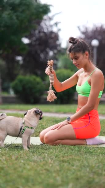 Летний Парк Показывает Девушка Спортивной Одежде Развлекается Своей Собакой Мопсом — стоковое видео