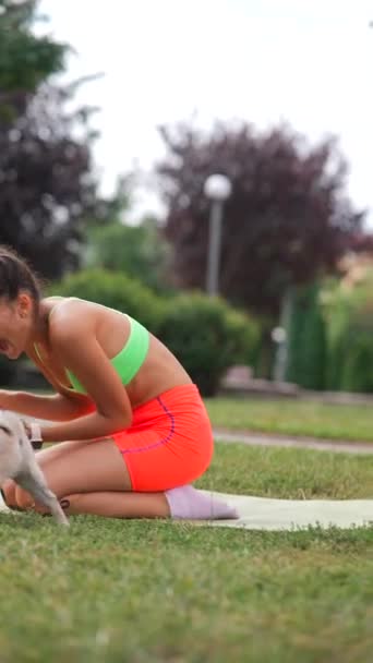 一个身穿运动服的漂亮姑娘在夏天的公园里和她那只哈巴狗嬉闹着玩耍 高质量的4K镜头 — 图库视频影像
