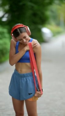 Koşusundan önce, spor giyimli genç bir kadın ısınma turu için bir fitness bandı kullanıyor. Yüksek kalite 4k görüntü