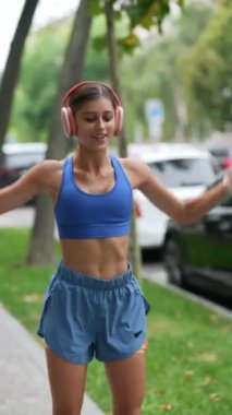 Spor kıyafetli genç bir kız koşuya çıkmadan önce vücudunu esneme hareketleriyle hazırlıyor. Yüksek kalite 4k görüntü