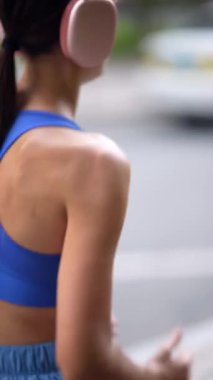 Manzara, spor kıyafetleri giymiş genç bir bayan olarak şehir sokaklarında koşuyor. Yüksek kalite 4k görüntü