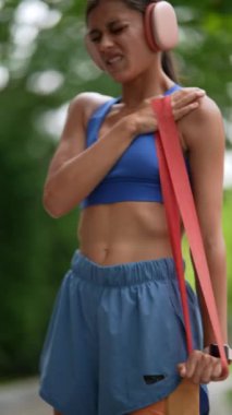Koşmadan önce, spor kıyafetleri içindeki genç bir kız spor bandıyla esneme egzersizleri yapıyor. Yüksek kalite 4k görüntü