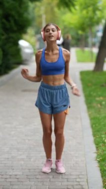 Spor kıyafetli genç bir kadın koşusundan önce vücudunu ısınma egzersizleriyle hazırlıyor. Yüksek kalite 4k görüntü