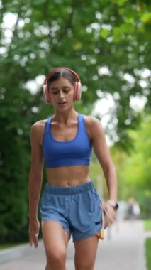 Spor kıyafetleri giyen genç bir kadın koşusundan önce vücudunu ısıtıyor. Yüksek kalite 4k görüntü