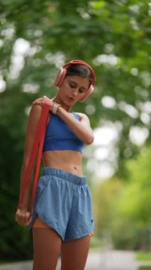 Spor giyimli genç bir kadın koşusundan önce spor bandıyla esneme egzersizleri yapıyor. Yüksek kalite 4k görüntü