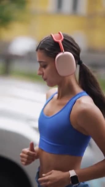 这位戴着耳机的年轻女运动员精疲力尽地跑过了城市的街道 高质量的4K镜头 — 图库视频影像