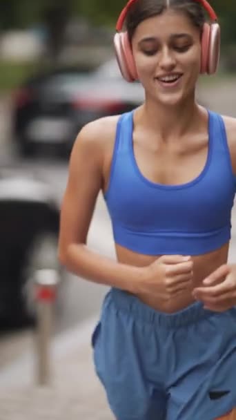 운동복과 헤드폰을 여성이 도시의 거리를 달리고 있습니다 고품질 — 비디오