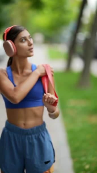 一位穿着运动服的年轻女士在跑步前正在用一个抵抗带进行热身 高质量的4K镜头 — 图库视频影像