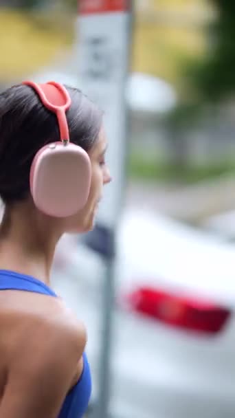 一个城市景观背景作为一个年轻的女士穿着运动服和耳机跑过 高质量的4K镜头 — 图库视频影像