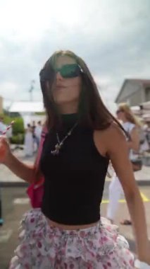 Güneş gözlüğü takan genç bir bayan yaz festivalinde coşkuyla dans ediyor. Yüksek kalite 4k görüntü