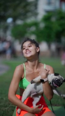 Spor kıyafetli güzel bir kız, sabah sporu sırasında köpeğiyle parkta oynar. Yüksek kalite 4k görüntü