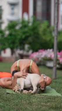 Sabah egzersizi sırasında, spor kıyafetleri içindeki güzel genç bir kadın parkta köpeğiyle oynaşıyor. Yüksek kalite 4k görüntü