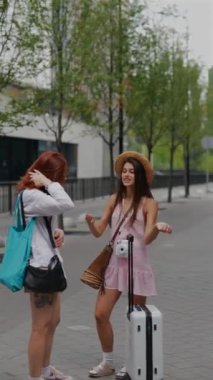 Şehrin sokaklarında, bavulları ve çantaları olan iki arkadaş kelimeleri değiş tokuş ediyor. Yüksek kalite 4k görüntü