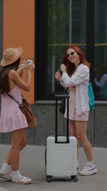 İki genç ve enerjik kız, şehirde birbirlerini fotoğraflıyorlar. Yüksek kalite 4k görüntü