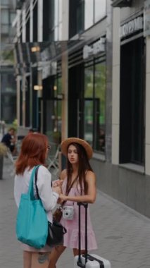 Şehir ortamında, bavulları ve çantaları olan iki arkadaş birbirleriyle bir şeyler tartışıyor. Yüksek kalite 4k görüntü