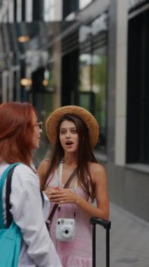 Valizli ve çantalı iki arkadaş şehir sokaklarında yürürken sohbet ediyorlar. Yüksek kalite 4k görüntü