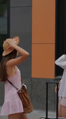 Şehir zemininin ortasında, iki enerjik genç kadın birbirlerinin fotoğraflarını çekiyor. Yüksek kalite 4k görüntü