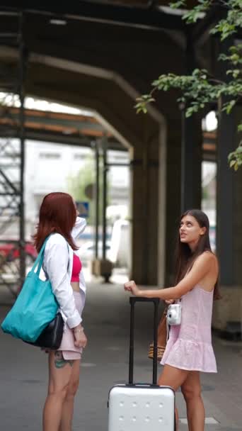 在城市的喧嚣和喧嚣中 两位年轻迷人的女士提着包和一个手提箱互相交谈着 高质量的4K镜头 — 图库视频影像